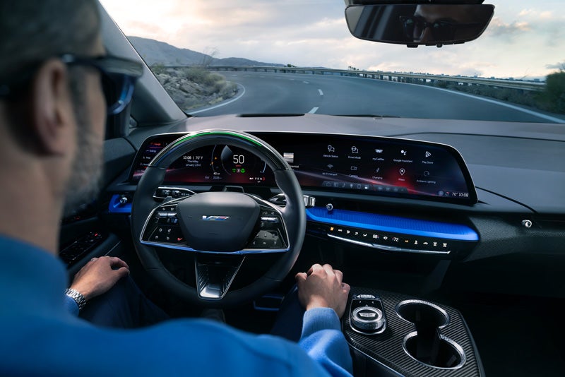 Front View of the 2026 OPTIQ-V Driving Through the Dusk Utilizing its Headlights | Ghent Cadillac in Greeley CO