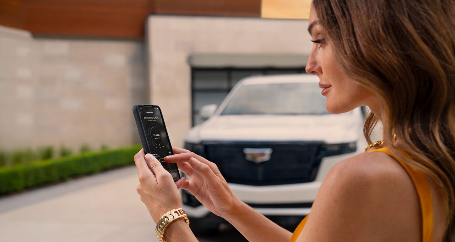 lady checking her mobile with a Cadillac vehicle background | Ghent Cadillac in Greeley CO